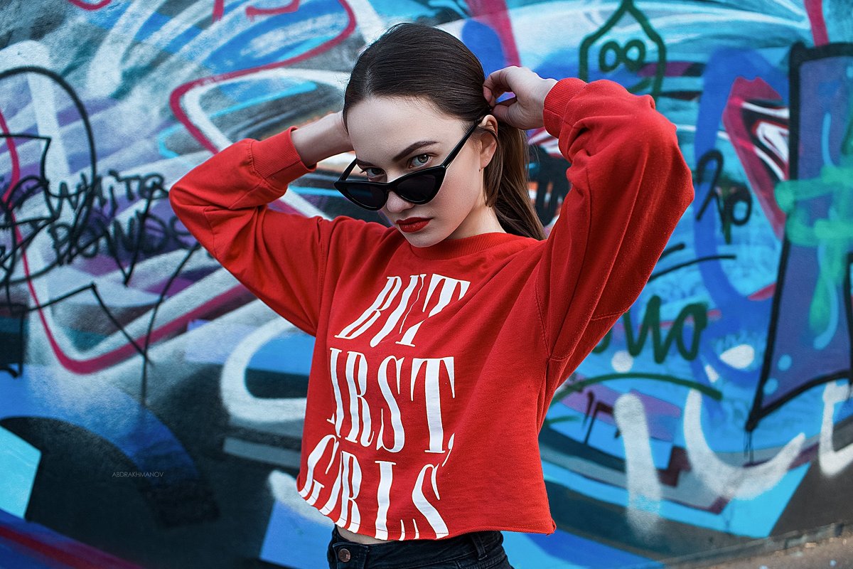 Портрет девушки в очках и красной толстовке на фоне стены с граффити - Lenar Abdrakhmanov