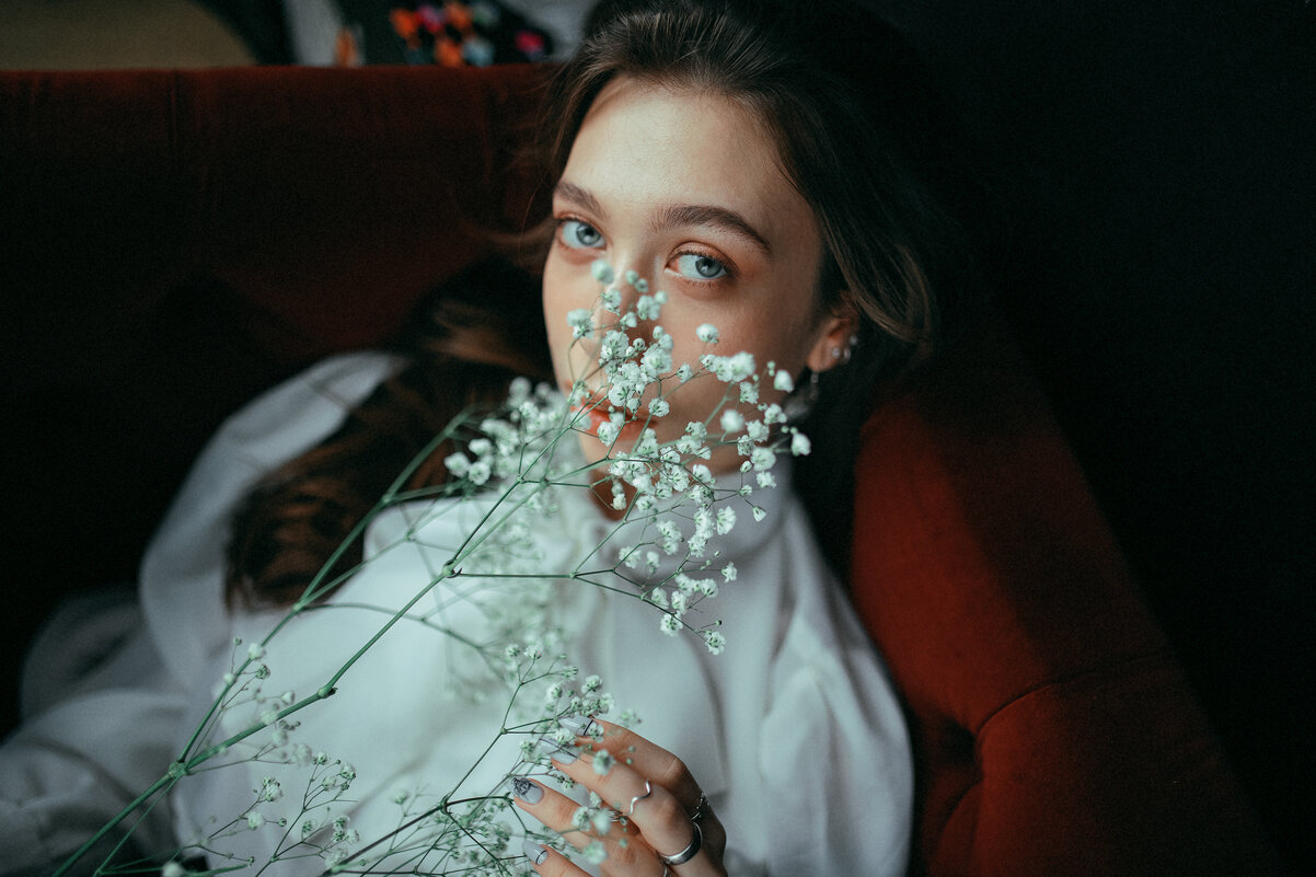 Девушка в белой рубашке с цветком в руке лежит на красном диване - Lenar Abdrakhmanov