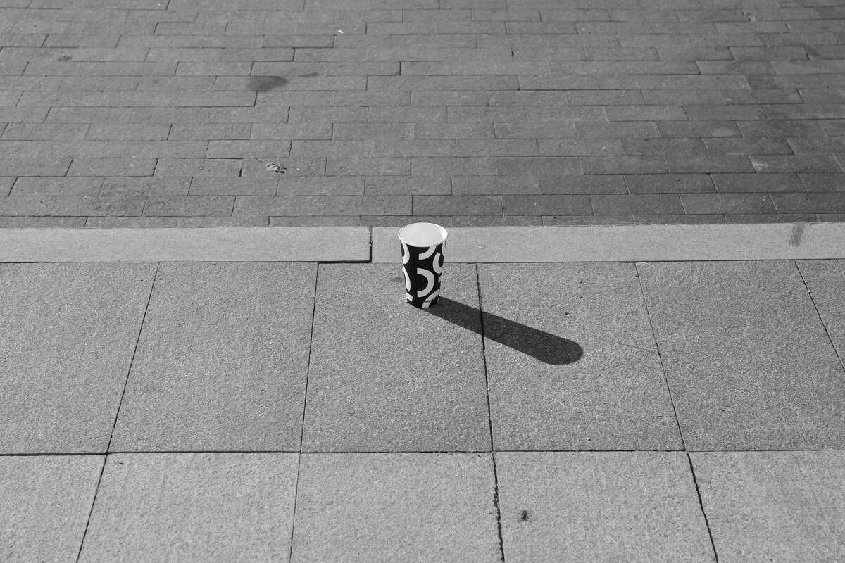 Пустой стакан на тратуаре отбрасывающий тень - Денис Безногов